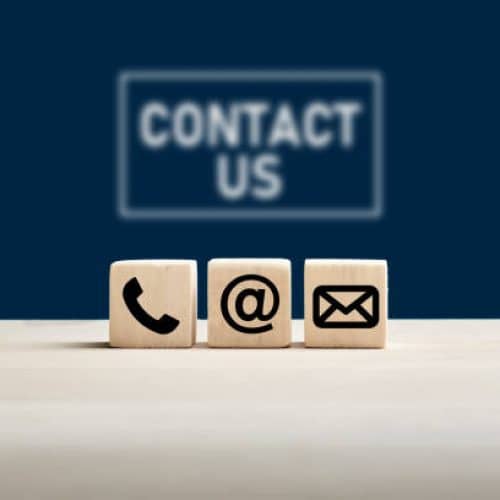 Phone and e-mail icons on wooden cubes with contact us text on blue background. Website page contact us or e-mail marketing concept.